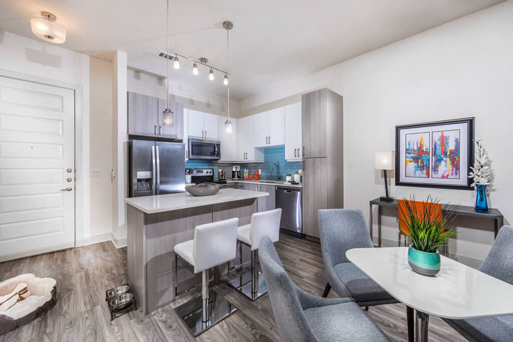 A dining table overlooking a modern kitchen at the Inwood Station Apartments in Dallas, Texas.